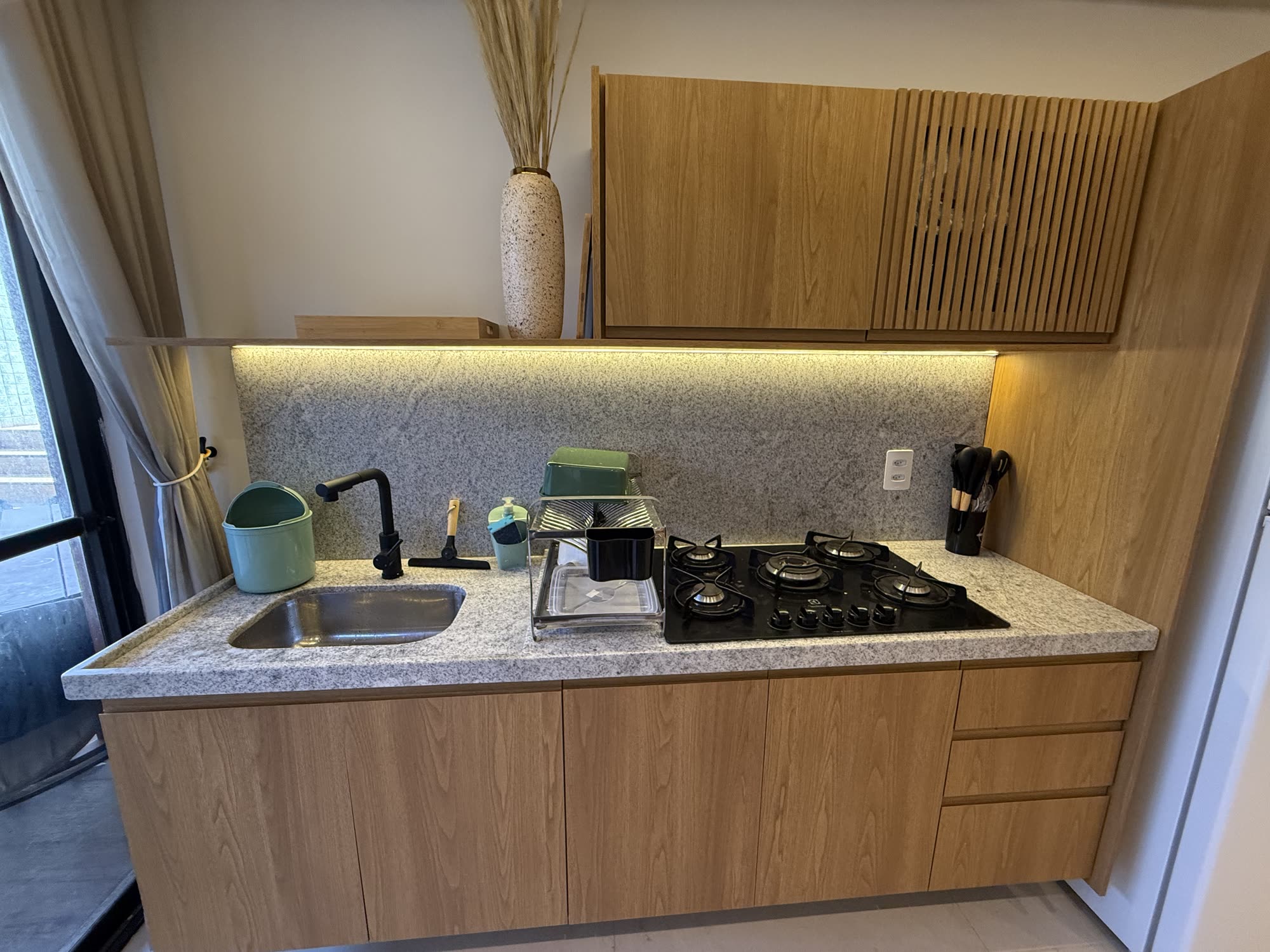 Cozinha com bancada de granito, cooktop e armários em madeira